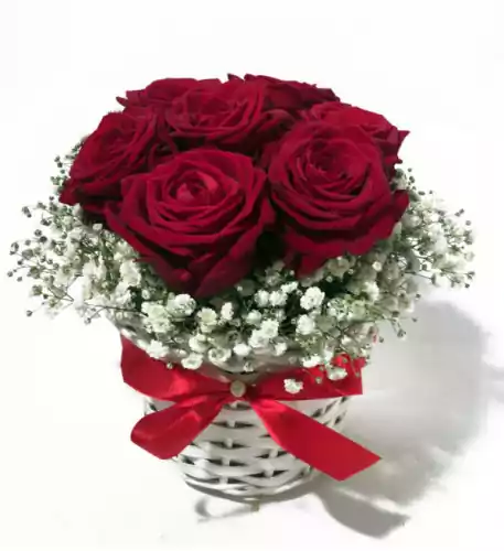 Arrangement of red roses in a small white basket